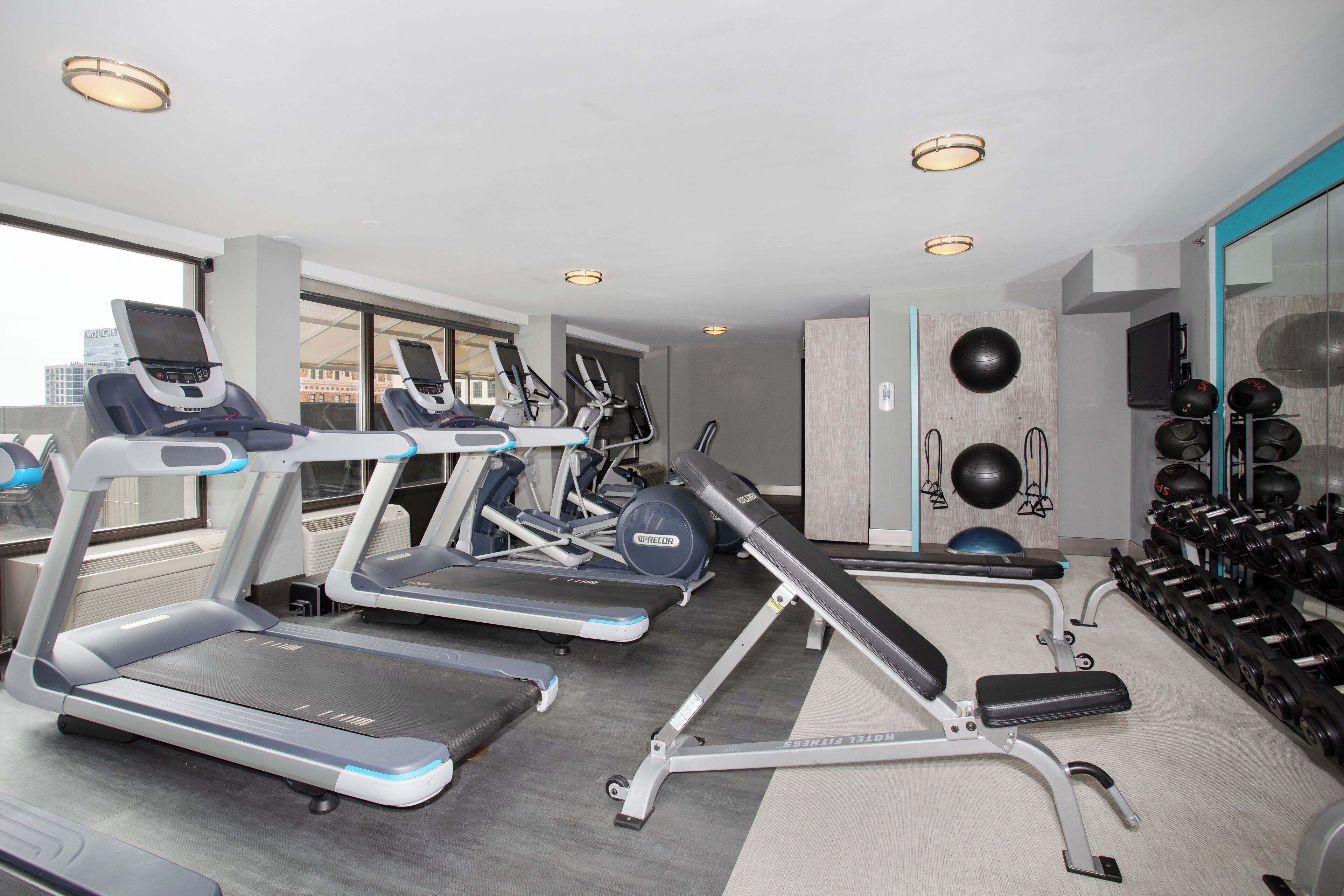 A modern gym with treadmills, elliptical machines, and a variety of weights.
