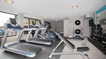 A modern gym with treadmills, elliptical machines, and a variety of weights.