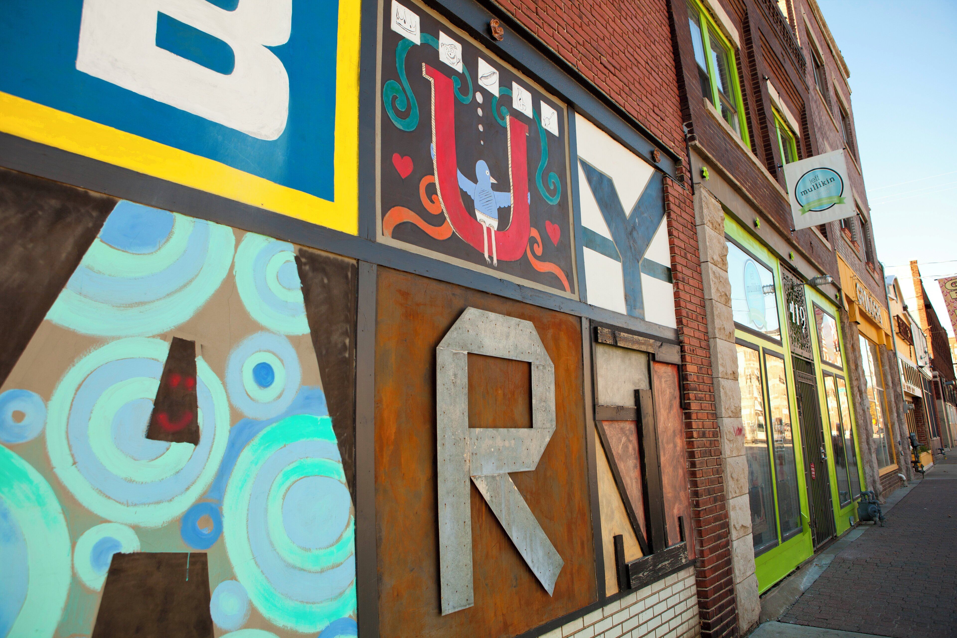 A building with a large, colorful mural on the side, including letters and abstract designs.