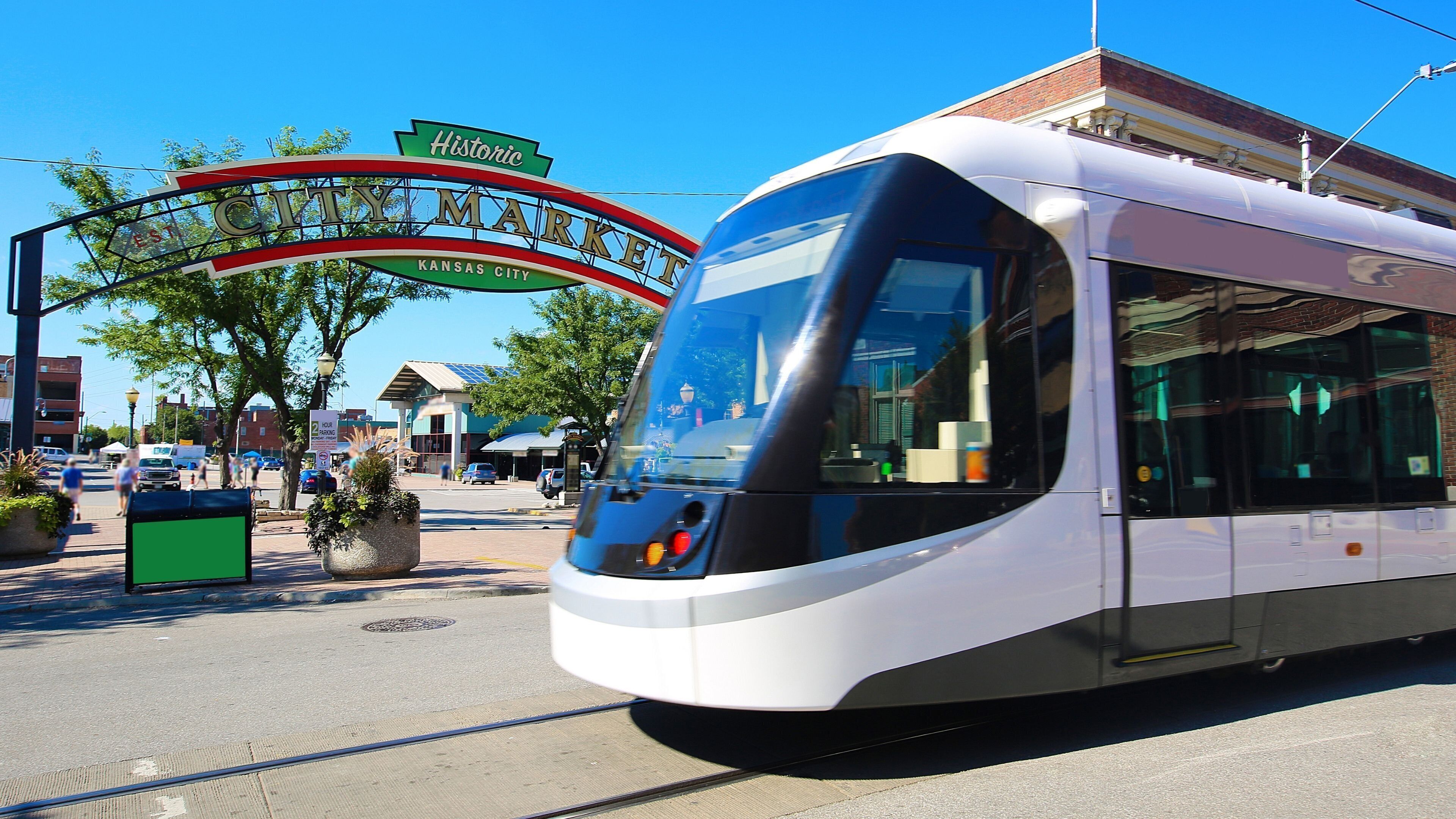 A modern tram at a tram station with a historic sign above.