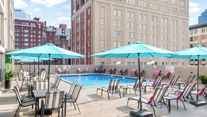 A rooftop pool area with lounge chairs and umbrellas, surrounded by historic buildings. - Crowne Plaza Kansas City Downtown by IHG (Kansas City)