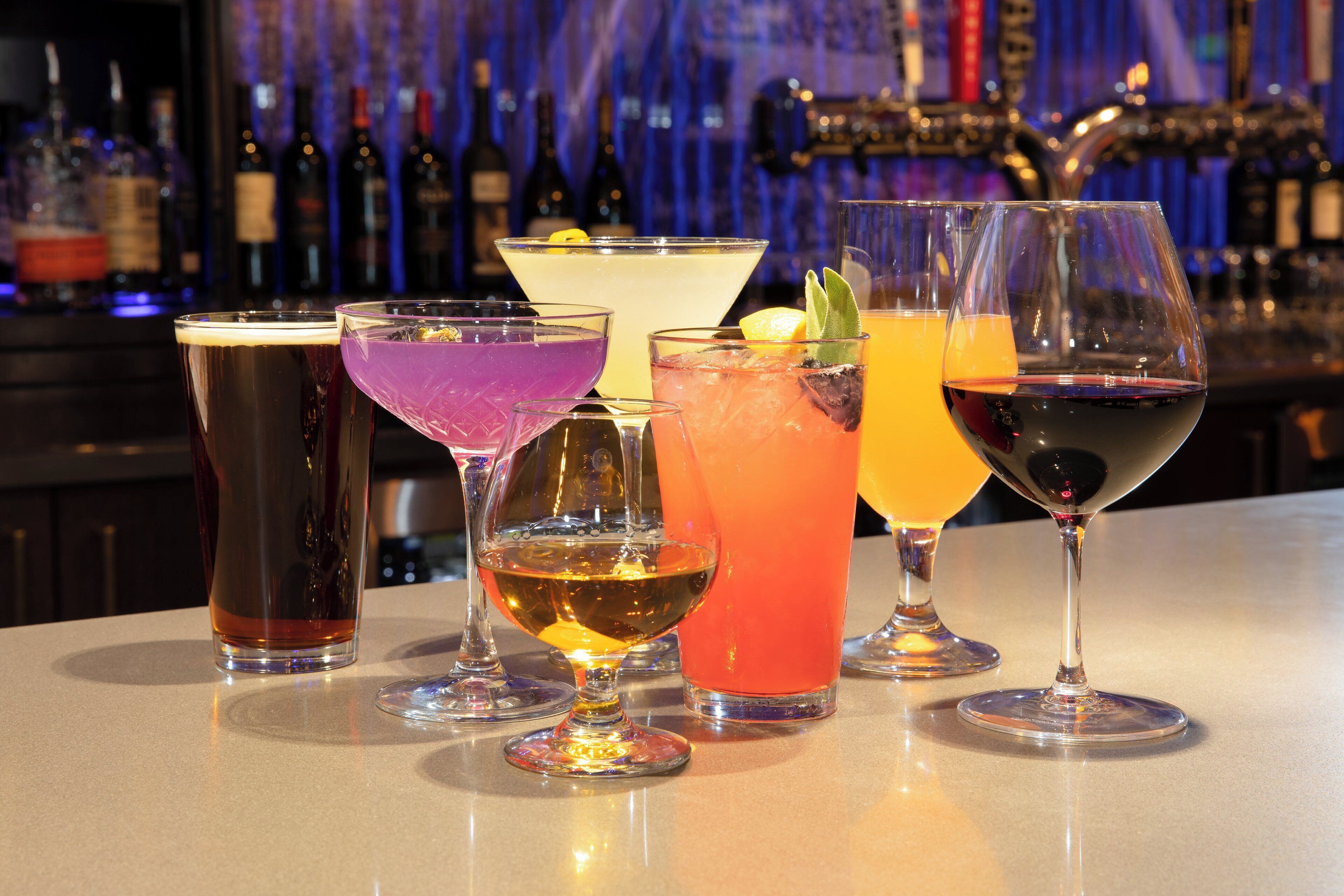Een bar met verschillende glazen en flessen drank in de achtergrond.