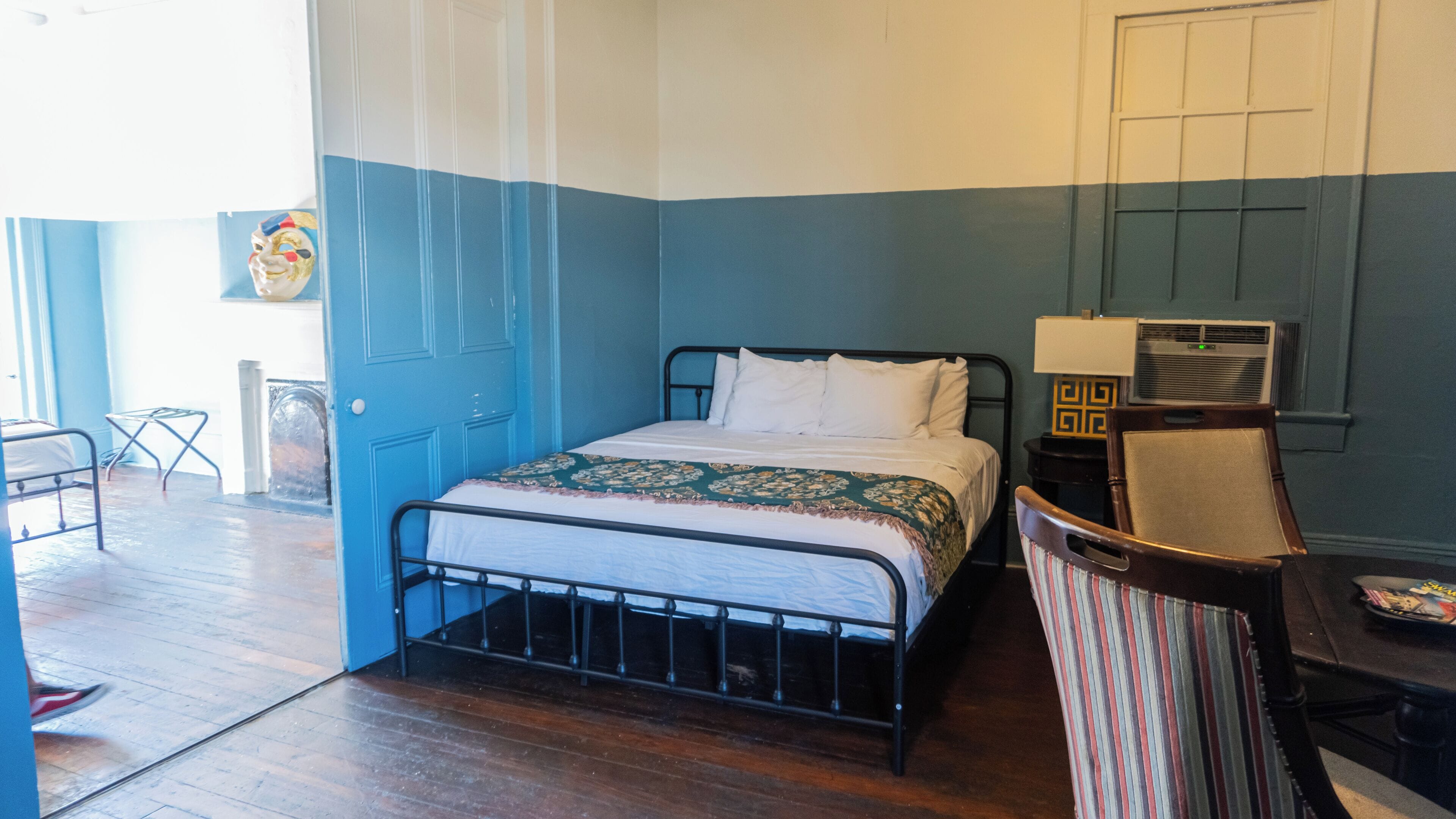 A bedroom with a bed, a chair, a table, and a door.