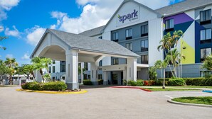 A modern hotel with a covered entrance, palm trees, and a clear blue sky.
