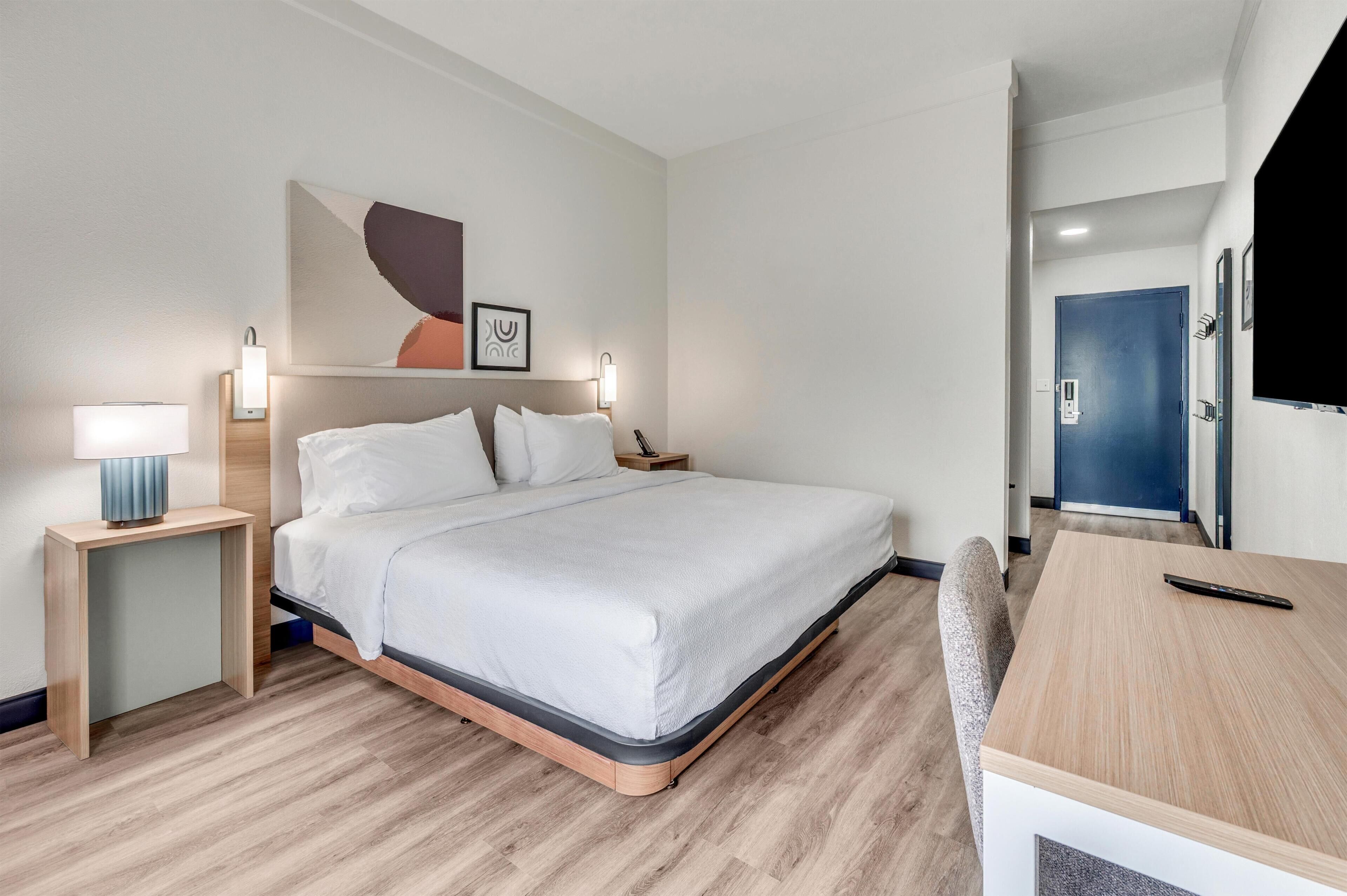 Una habitación de hotel con cama, mesitas de noche, escritorio y una silla.