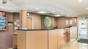 A reception desk with a clock, a wall-mounted decorative piece, and a sign indicating 'The Market'. - Fairfield Inn & Suites By Marriott - Brunswick (Brunswick)