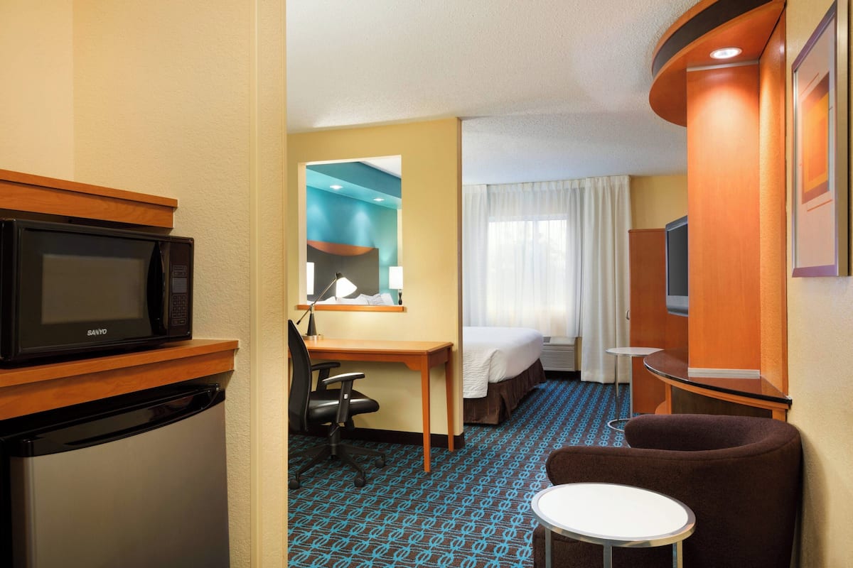 Une chambre d’hôtel équipée d’un micro-ondes, d’un bureau, d’une chaise, d’un lit et d’une petite table.