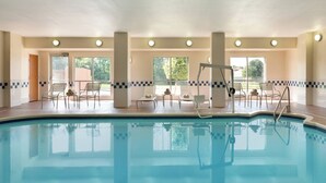 Ein Hallenbad mit klarem, blauem Wasser, umgeben von Liegestühlen und einer gefliesten Bordüre.