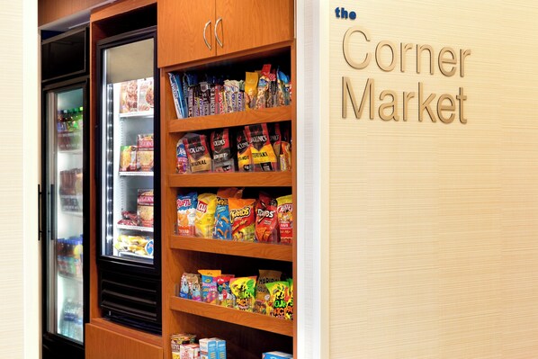 A snack display in a store with various packaged snacks and a refrigerated section.