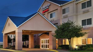 Ein Fairfield Inn & Suites Marriott Hotel mit überdachter Eingangszone und einem begrünten Vorgarten.