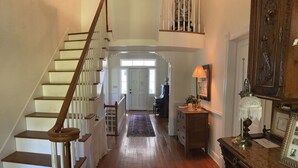 A wooden staircase leading to a landing with a piano and a desk with a lamp.