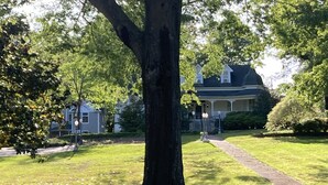 A residential area with a large tree, a pathway leading to a house, and a well-maintained lawn.