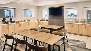 A modern kitchen with wooden cabinets, a central island, and a flat-screen TV.