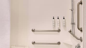 A modern bathroom with a walk-in shower, grab bars, a bathtub, and a towel rack.