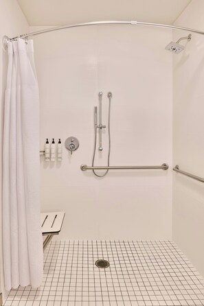 A walk-in shower with a grab bar, a white shower curtain, and a grid-patterned floor. - Springhill Suites By Marriott Phoenix Glendale Peoria (Glendale)