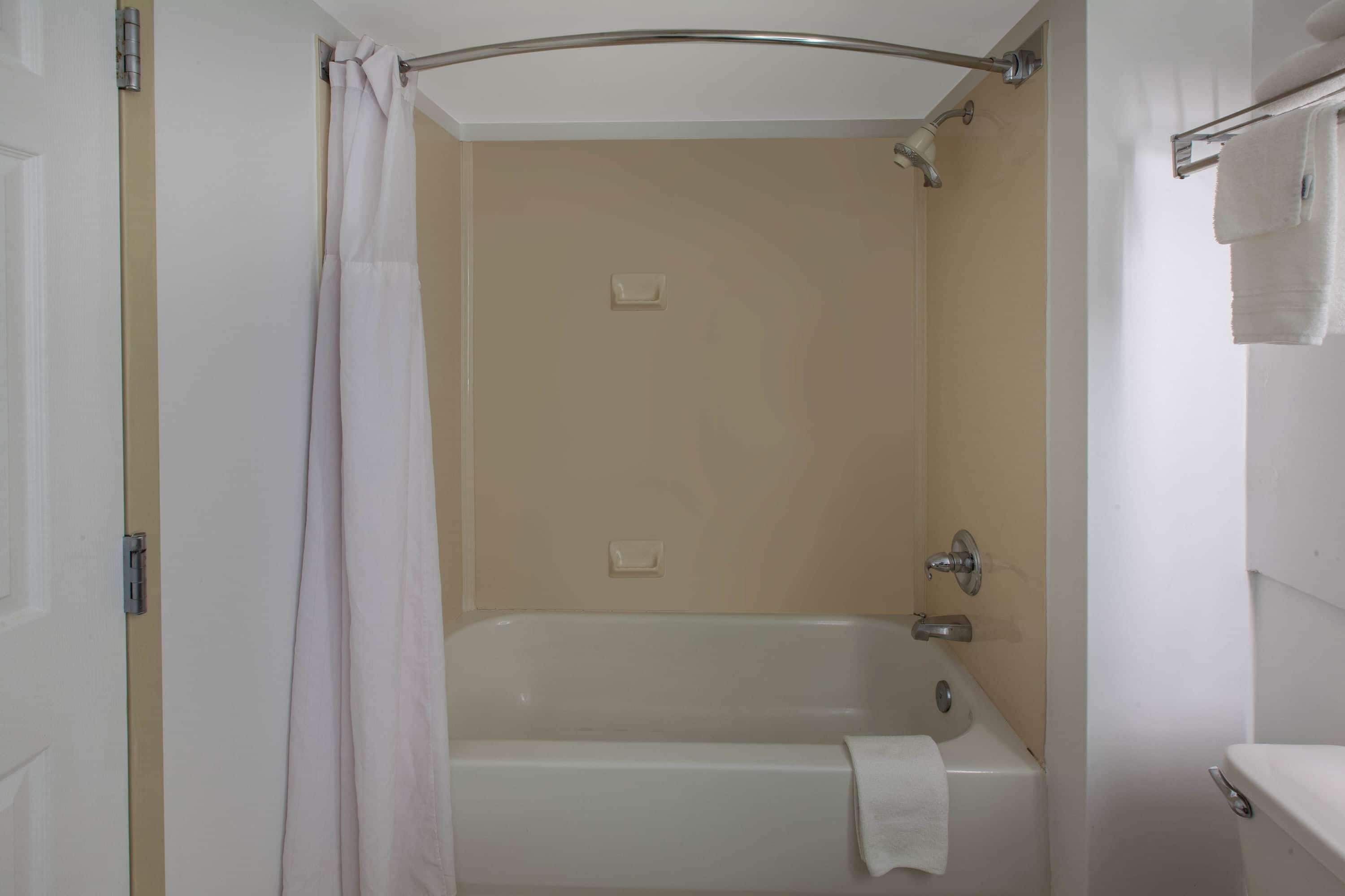 A bathroom with a bathtub, a shower curtain, and a towel rack.