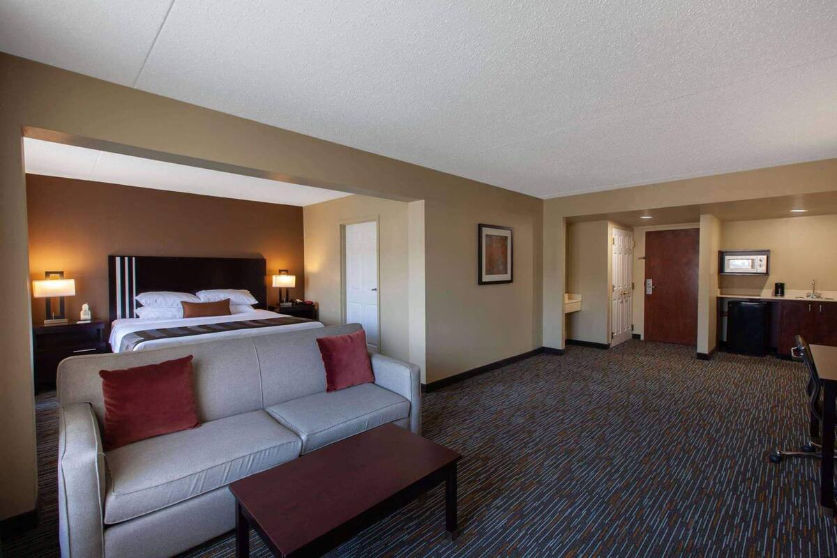 Ein Hotelzimmer mit Bett, einer Couch, einem Couchtisch, einem Schreibtisch und einer Küchenzeile.