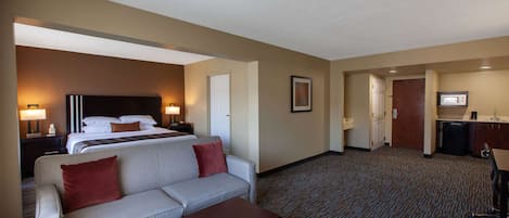 Une chambre d’hôtel comprenant un lit, un canapé, une table basse, un bureau et une kitchenette.