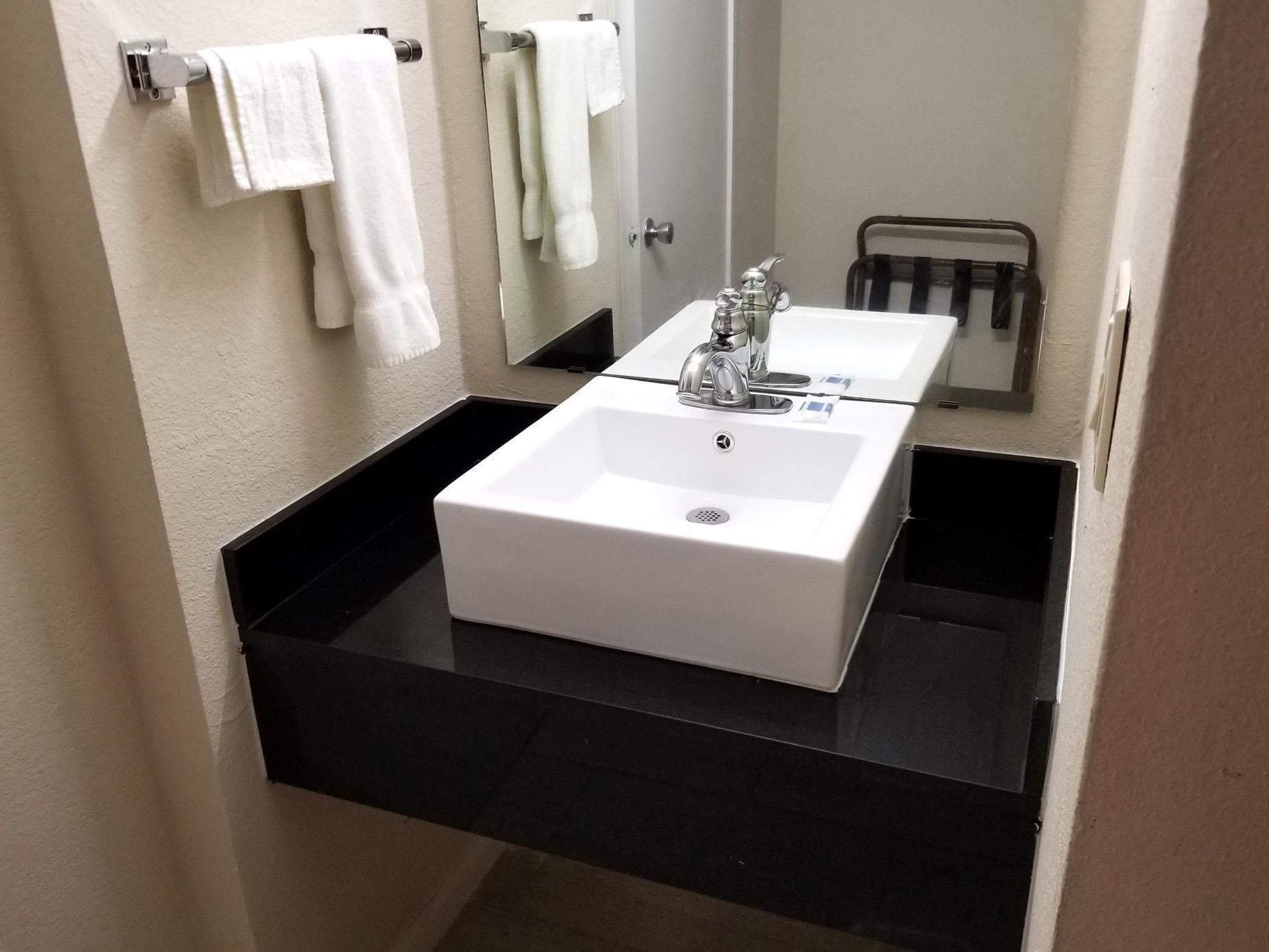 A bathroom with a white sink, black countertop, and a mirror above it.