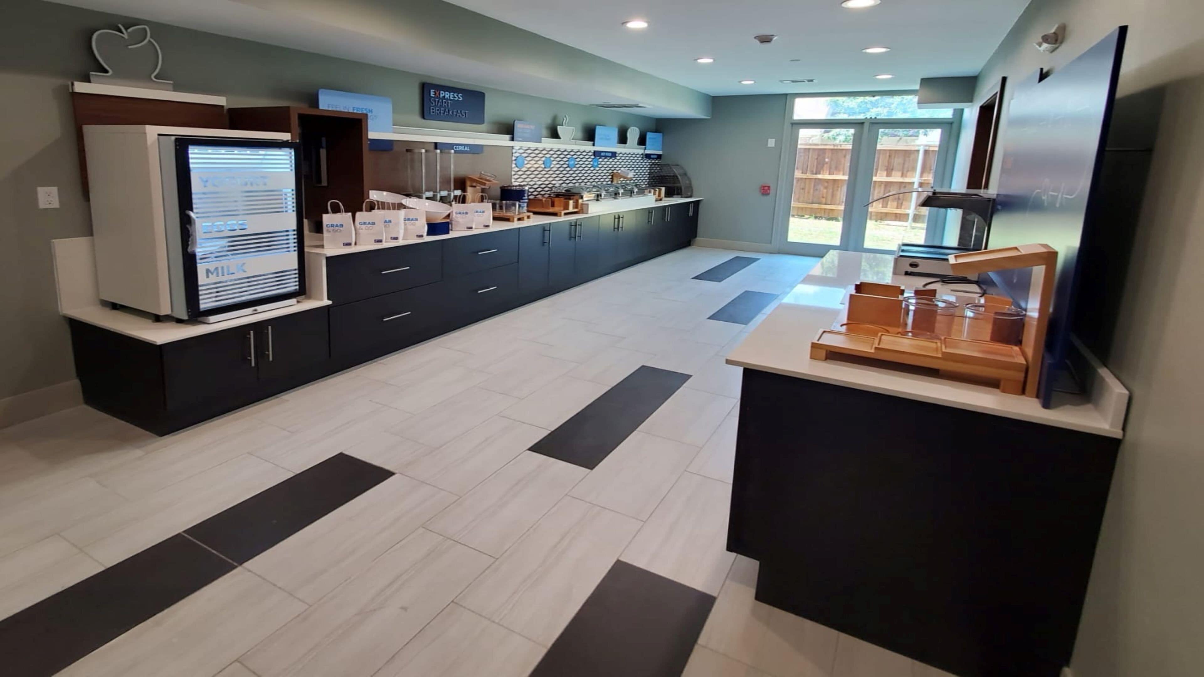 A modern kitchen area with a refrigerator, a coffee machine, and a counter with a coffee dispenser.