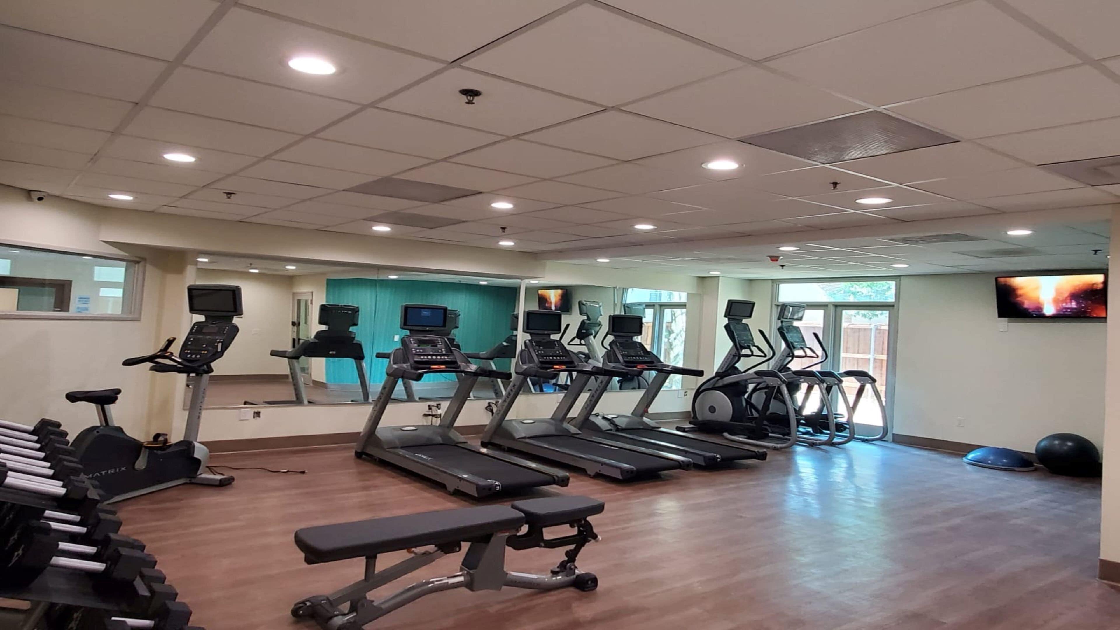 A gym with treadmills, exercise bikes, and free weights.