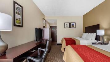 A hotel room with a bed, a desk with a chair, a television, and a lamp.