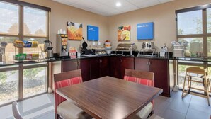 A modern kitchen with a dining area, featuring a large table and chairs, a coffee station, and breakfast options. - Comfort Inn Horn Lake - Southhaven (Horn Lake)