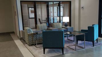 A modern lounge area with seating arrangements, a coffee table, and a decorative partition.