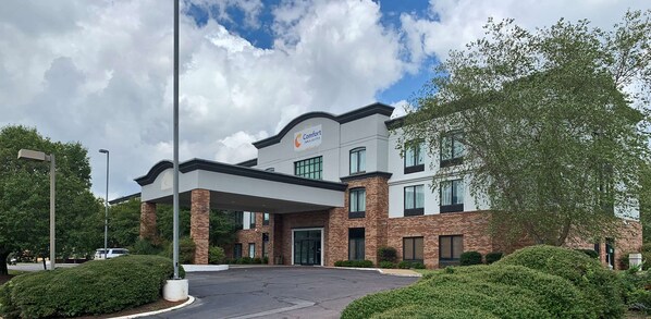 A modern hotel with a covered entrance, brick facade, and landscaped surroundings. - Comfort Inn & Suites Columbus North (Columbus)