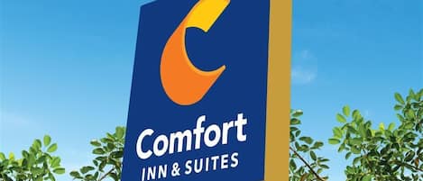 A sign for Comfort Inn & Suites with a stylized 'C' logo.