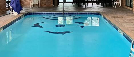 An indoor swimming pool with a clear blue water feature and a brick wall backdrop.