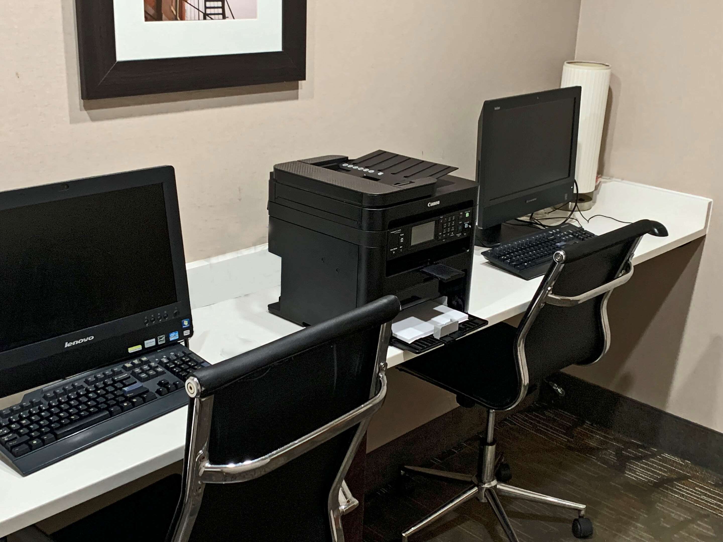 A workspace with two desktop computers, a Canon printer, and two black office chairs.