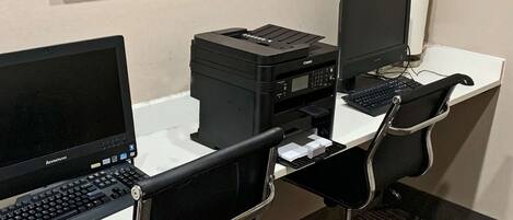 A workspace with two desktop computers, a Canon printer, and two black office chairs.