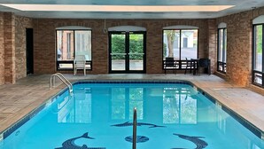 An indoor swimming pool with dolphin murals, brick walls, and large windows.