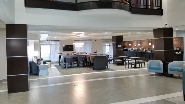 A spacious lobby with a curved balcony, a bar area, and seating arrangements.