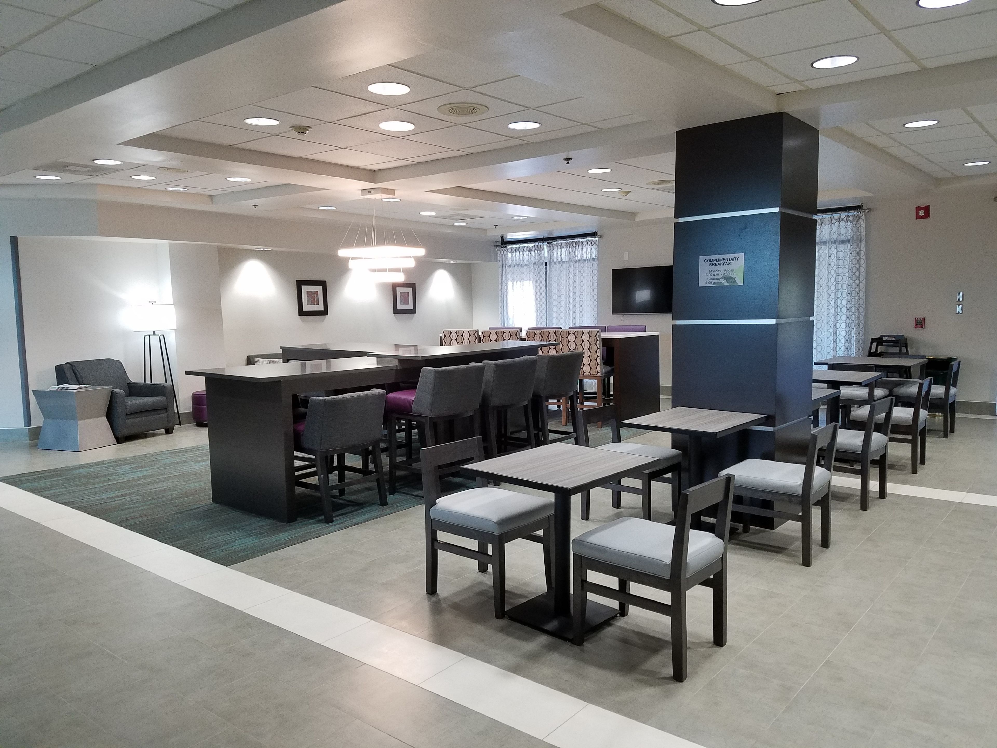 Een moderne hotellobby met een receptiebalie, een zithoek en een bar.