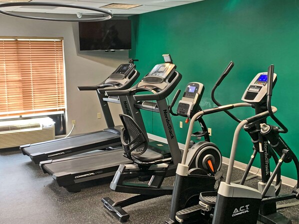 A gym with treadmills, a stationary bike, and a rowing machine.