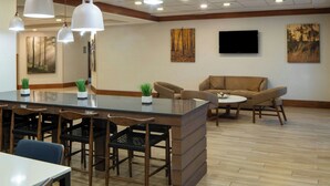 A modern interior with a dining area, sofas, and artwork on the walls. - Fairfield Inn & Suites Atlanta Airport South/Sullivan Road (College Park)