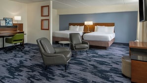 A hotel room with two beds, a desk, two armchairs, a small table, and a TV. - Fairfield Inn & Suites Atlanta Airport South/Sullivan Road (College Park)