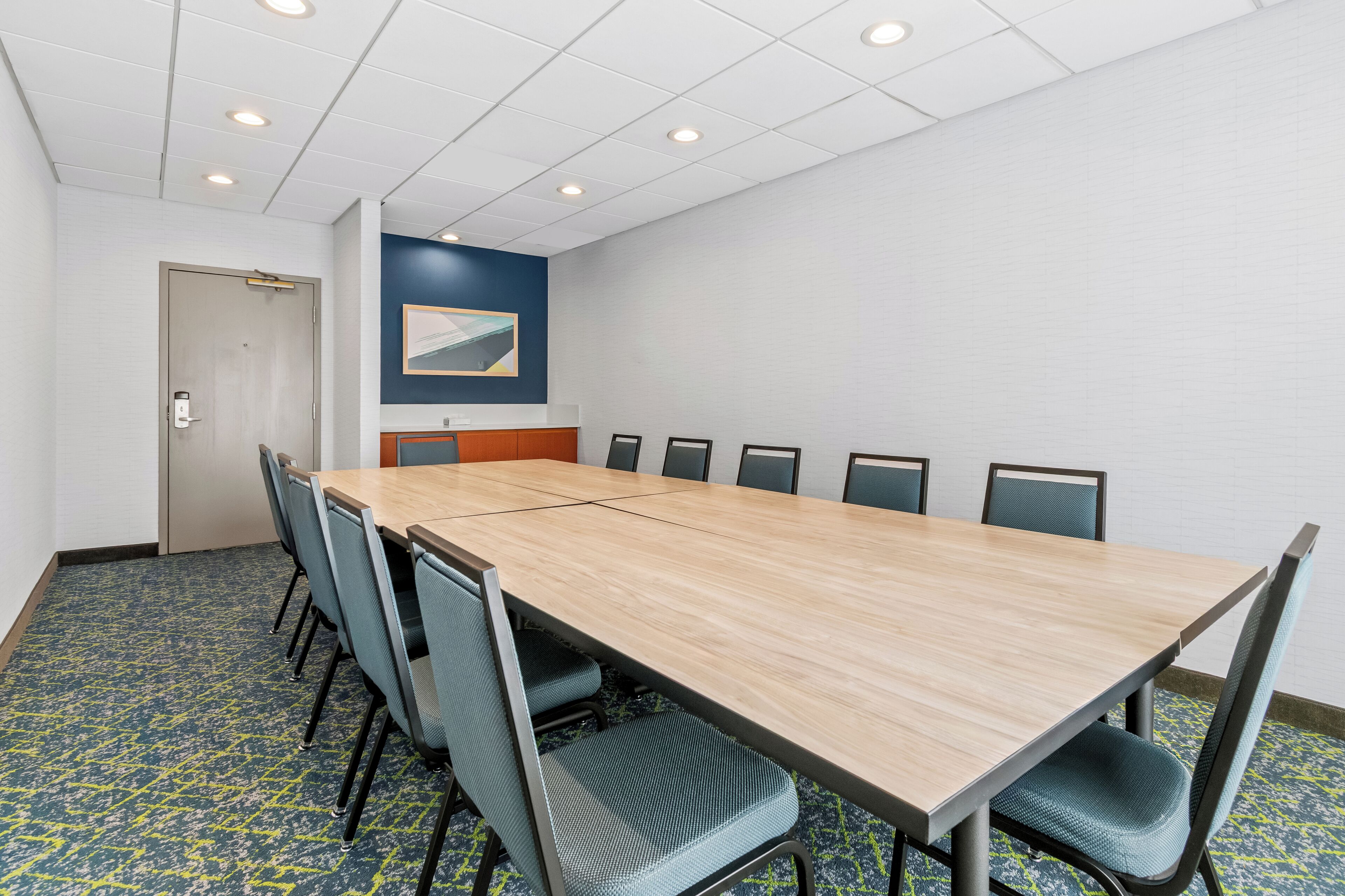 A conference room with a long table, chairs, and a door.