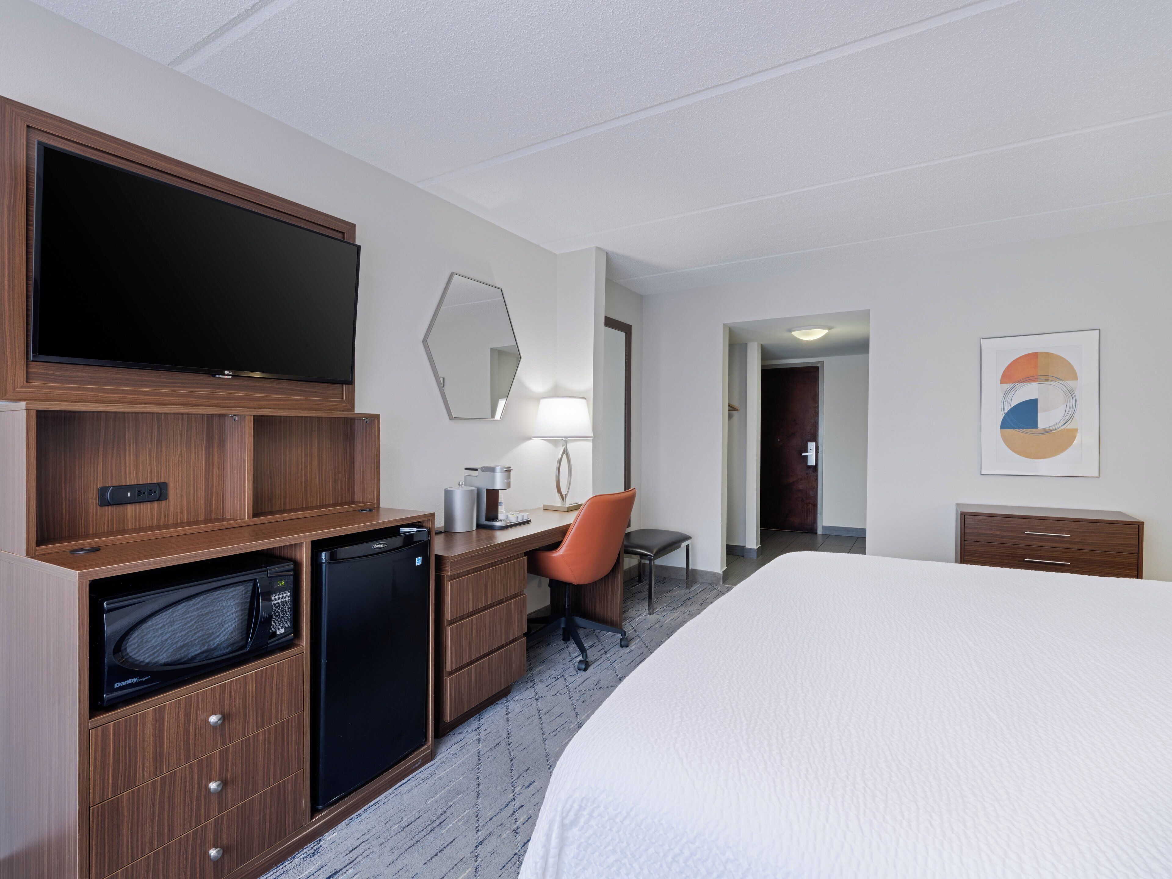 Hotelkamer met een bed, een bureau met stoel, een televisie, een magnetron en een koffiezetapparaat.