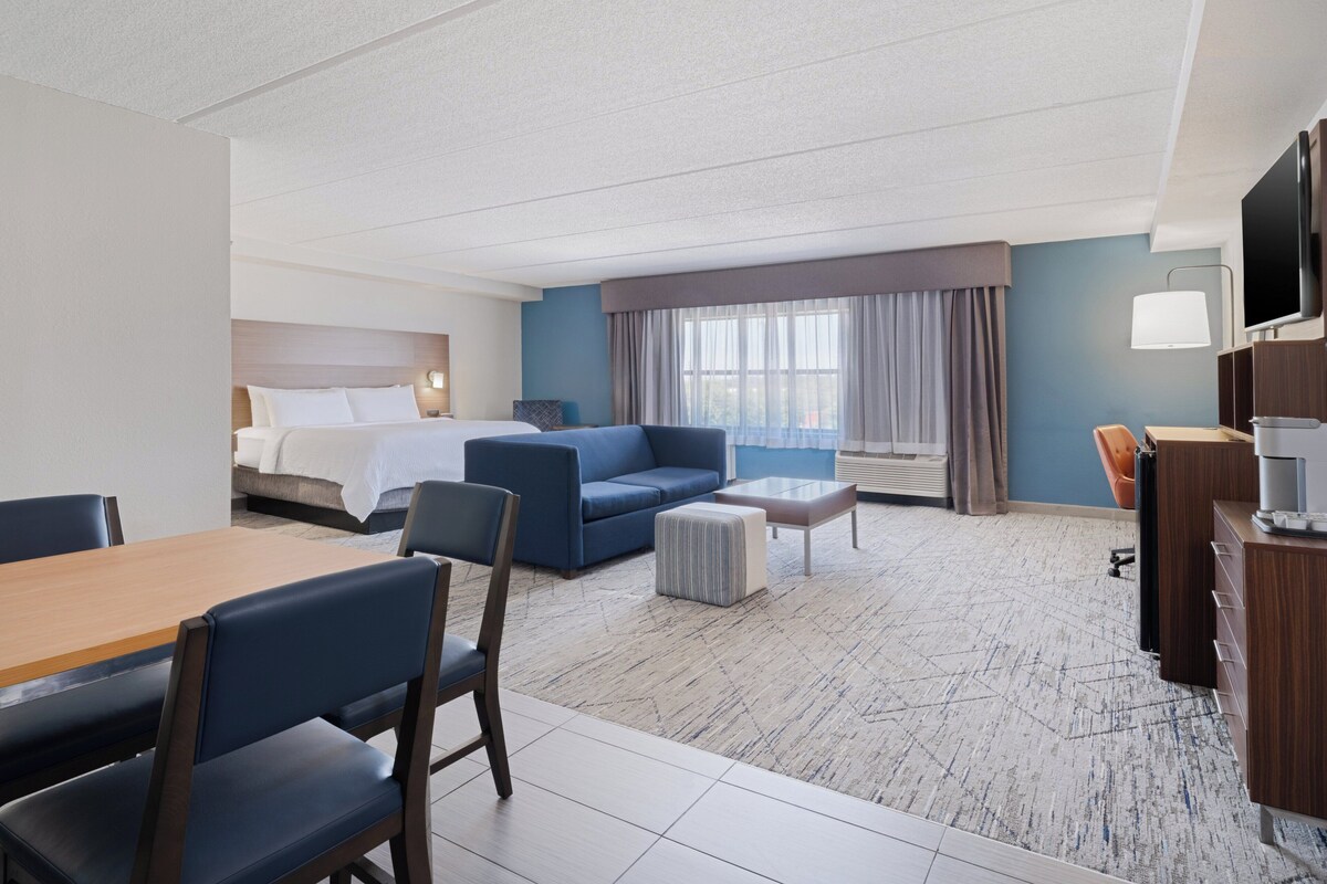 Une chambre d’hôtel équipée d’un lit, d’un canapé, d’une table à manger, de chaises, d’un téléviseur et d’une machine à café.