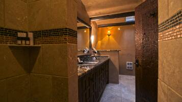 A bathroom with a tiled floor, a marble countertop, and a wooden door.