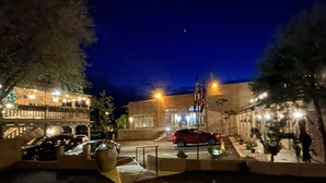 A nighttime view of a parking area with cars, a red vehicle, and a building with illuminated windows. - The Inn at Vanessie (Santa Fe)