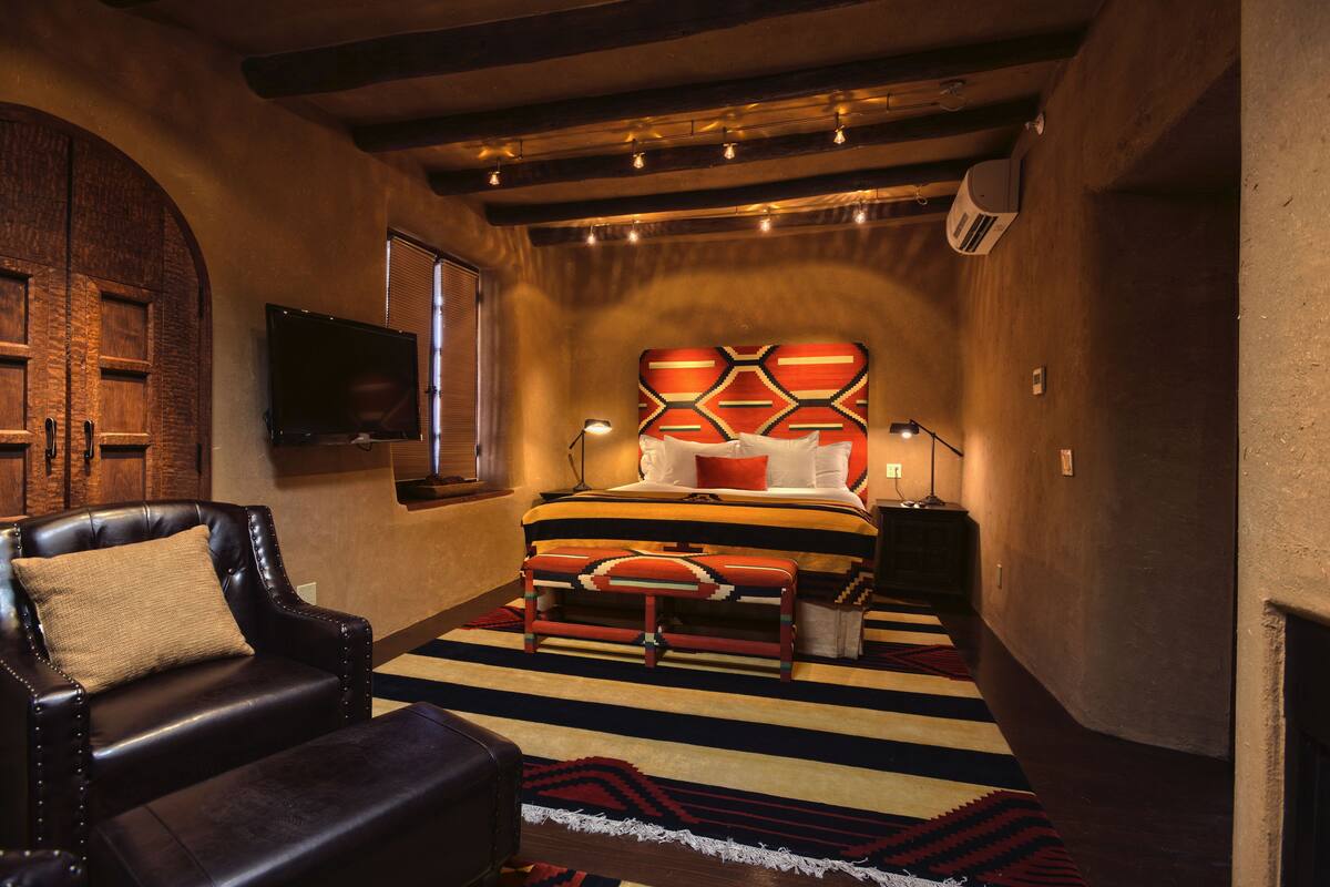A cozy bedroom with a bed, a leather chair, and a television on the wall.