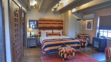 A bedroom with a large bed, two side tables, a chair, and a small table.