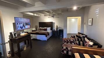 Una habitación de hotel con cama, sofá, televisor y ventilador de techo.