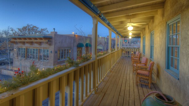 A wooden deck with chairs and a view of buildings. - The Inn at Vanessie (Santa Fe)