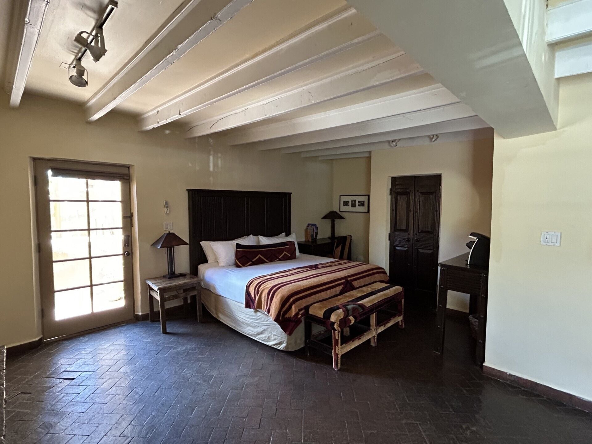 A bedroom with a bed, bedside tables, a desk, a chair, a wardrobe, and a ceiling fan.