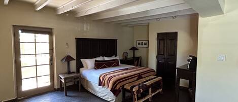 A bedroom with a bed, bedside tables, a desk, a chair, a wardrobe, and a ceiling fan.